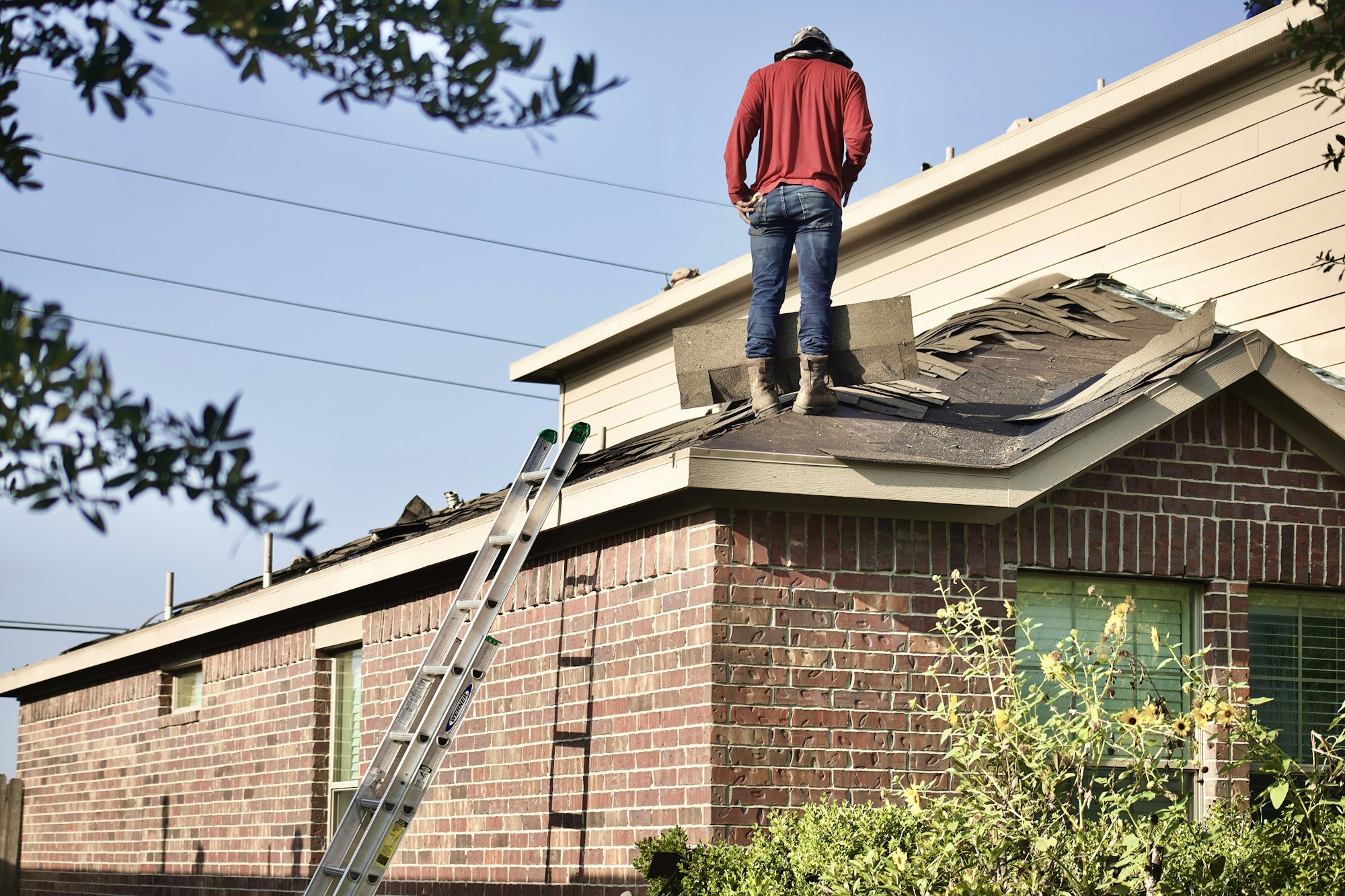 Roofing technician replacing shingles on a residential roof